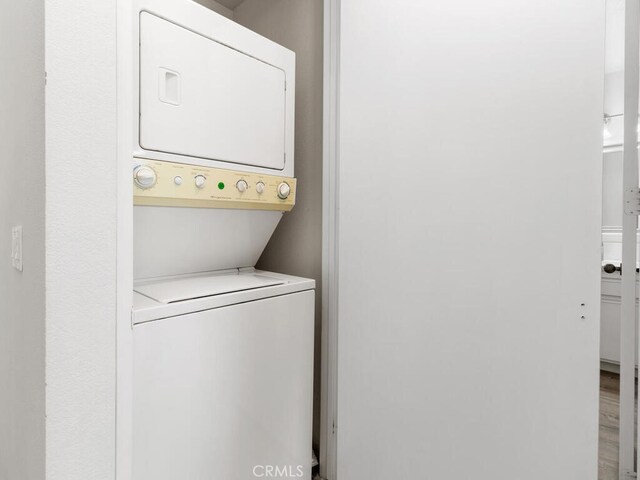 laundry room featuring stacked washer and dryer and hardwood / wood-style flooring