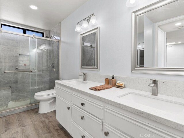 bathroom with vanity, a shower with shower door, toilet, and hardwood / wood-style flooring