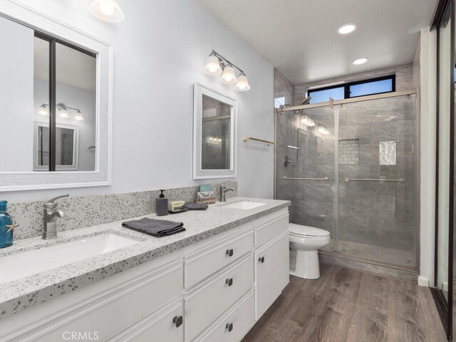 bathroom with hardwood / wood-style floors, vanity, toilet, and an enclosed shower