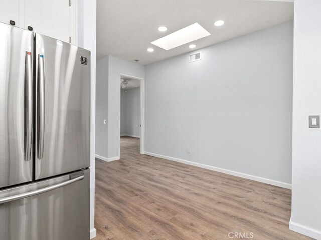 kitchen with light wood-type flooring, white cabinetry, and stainless steel refrigerator