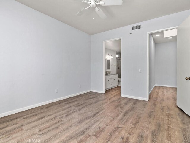 unfurnished bedroom with light wood-type flooring, ceiling fan, and ensuite bathroom