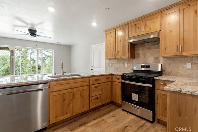 kitchen featuring sink, backsplash, stainless steel appliances, light stone countertops, and light hardwood / wood-style floors