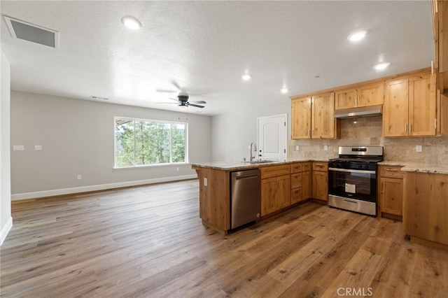 kitchen featuring light hardwood / wood-style floors, kitchen peninsula, light stone countertops, stainless steel appliances, and ceiling fan