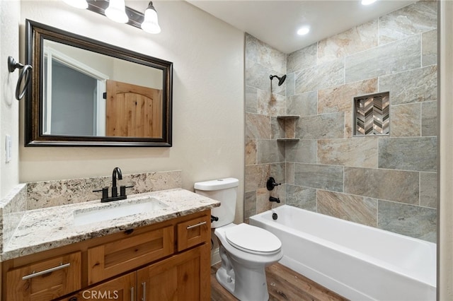 full bathroom featuring tiled shower / bath, hardwood / wood-style flooring, vanity, and toilet