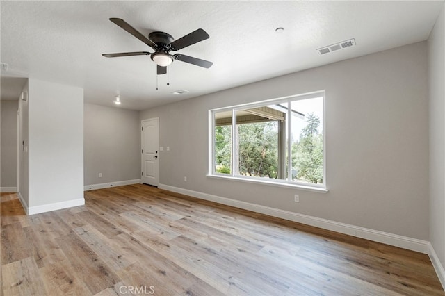 empty room with ceiling fan, a textured ceiling, and light hardwood / wood-style floors