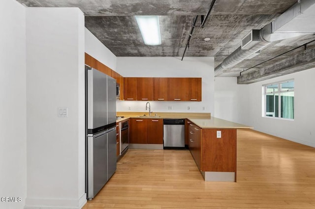 kitchen with kitchen peninsula, sink, light hardwood / wood-style flooring, and appliances with stainless steel finishes