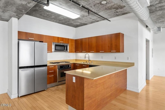 kitchen with track lighting, sink, light hardwood / wood-style flooring, kitchen peninsula, and stainless steel appliances