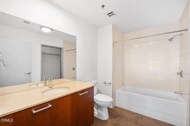 full bathroom with tile patterned flooring, vanity, tiled shower / bath combo, and toilet