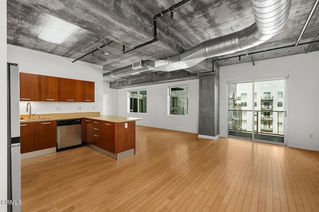 kitchen with kitchen peninsula, sink, stainless steel appliances, and light wood-type flooring