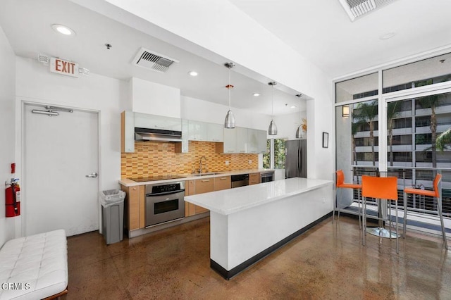 kitchen featuring kitchen peninsula, backsplash, stainless steel appliances, white cabinets, and hanging light fixtures