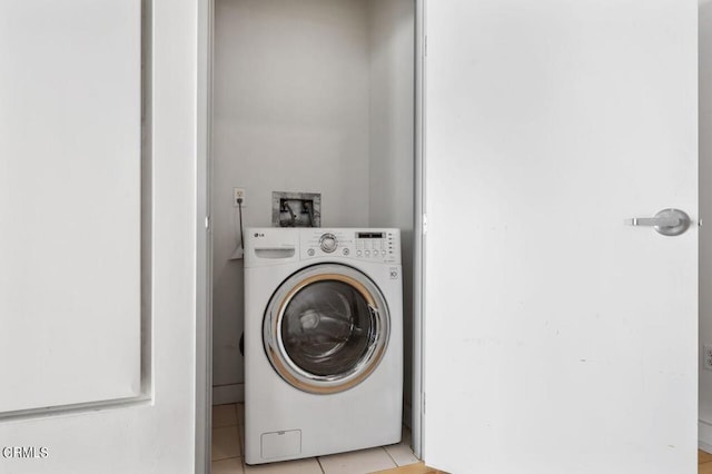 clothes washing area with washer / dryer and light tile patterned floors