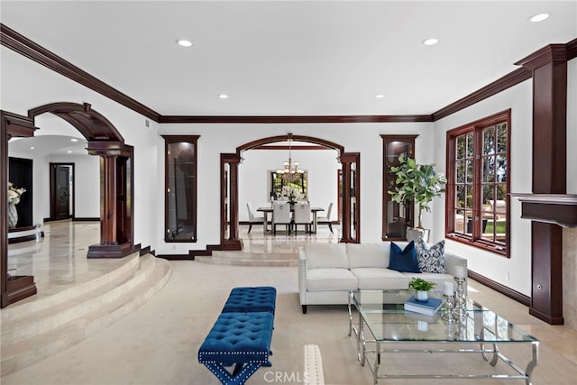 living room featuring a notable chandelier, decorative columns, and crown molding