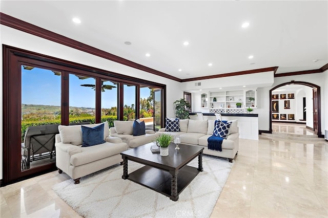 living room with ornamental molding and built in shelves