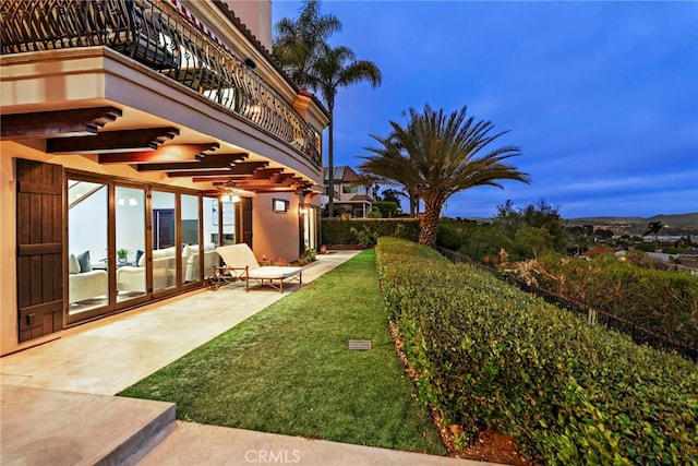 view of yard with ceiling fan, a balcony, and a patio