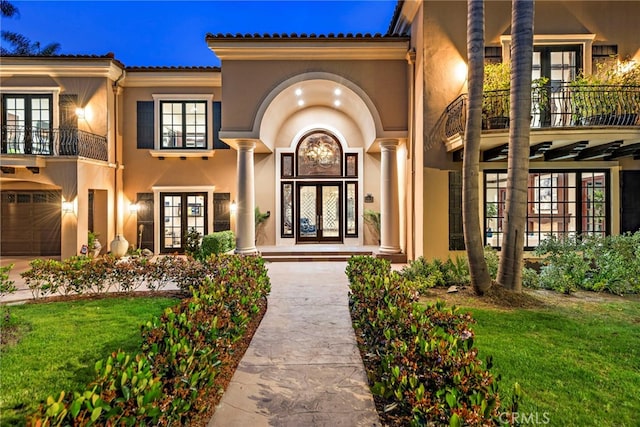 view of front of home featuring a balcony, a front lawn, and french doors