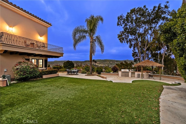 yard at dusk featuring a gazebo, area for grilling, a balcony, and a patio area