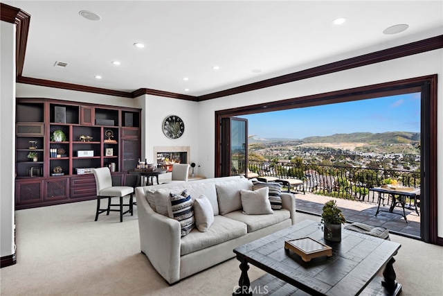 carpeted living room with ornamental molding and a mountain view