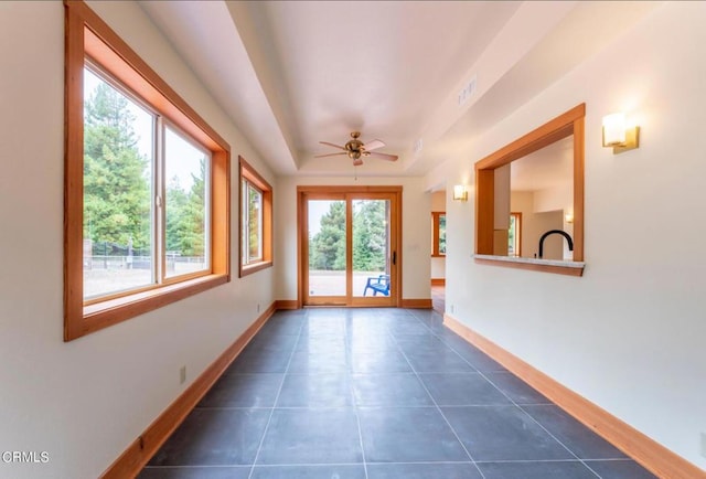 interior space with a tray ceiling, visible vents, and ceiling fan