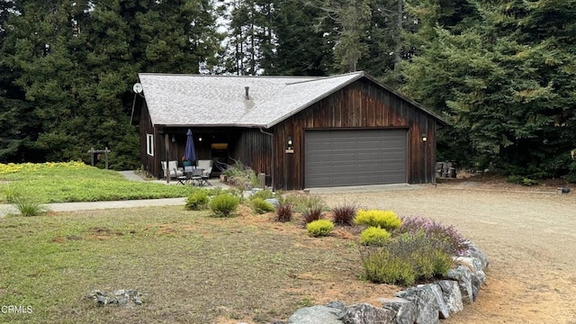 view of front of house featuring a garage, dirt driveway, a front yard, and an outdoor structure