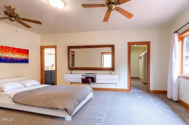 carpeted bedroom with ensuite bath and baseboards