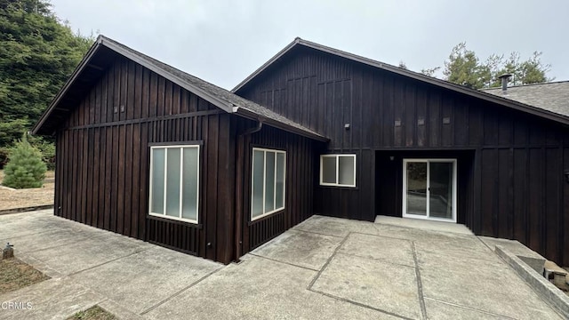 exterior space with a shingled roof and a patio area