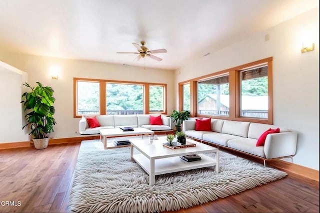 living area with wood finished floors, a ceiling fan, and baseboards