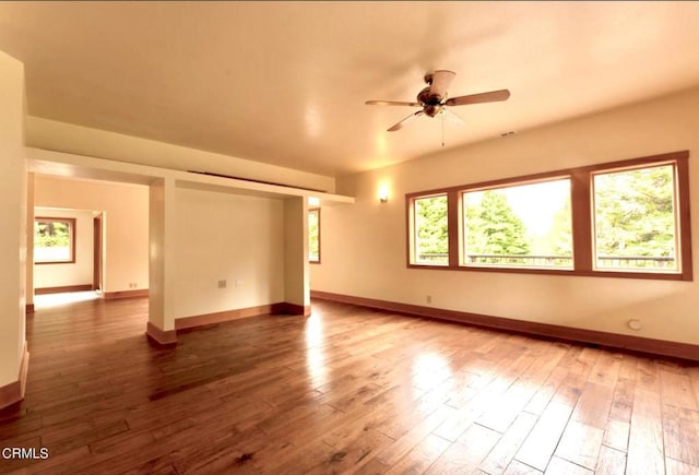 empty room with ceiling fan, hardwood / wood-style floors, and baseboards