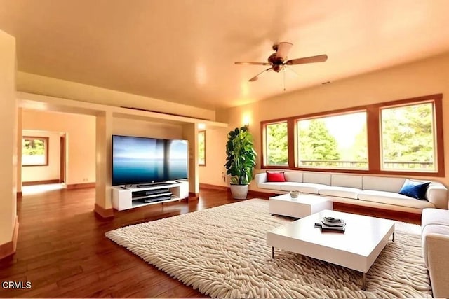 living area featuring ceiling fan, baseboards, and wood finished floors