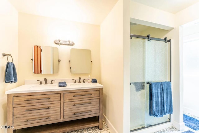 bathroom with double vanity, a shower stall, baseboards, and a sink