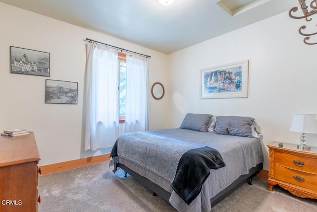 carpeted bedroom with attic access and baseboards