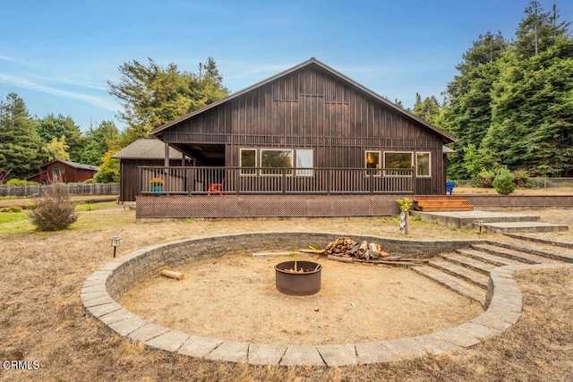 back of property with an outdoor fire pit and a wooden deck