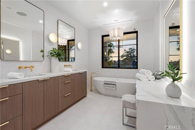 full bathroom with a sink, a soaking tub, tile walls, and double vanity