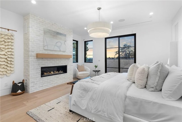 bedroom featuring recessed lighting, wood finished floors, a fireplace, and access to outside