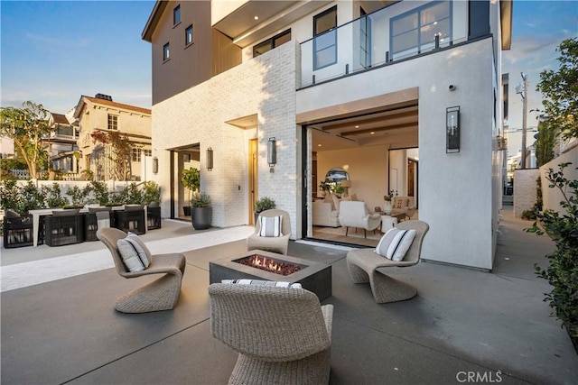 view of patio / terrace with an outdoor living space with a fire pit, a balcony, and outdoor dining space