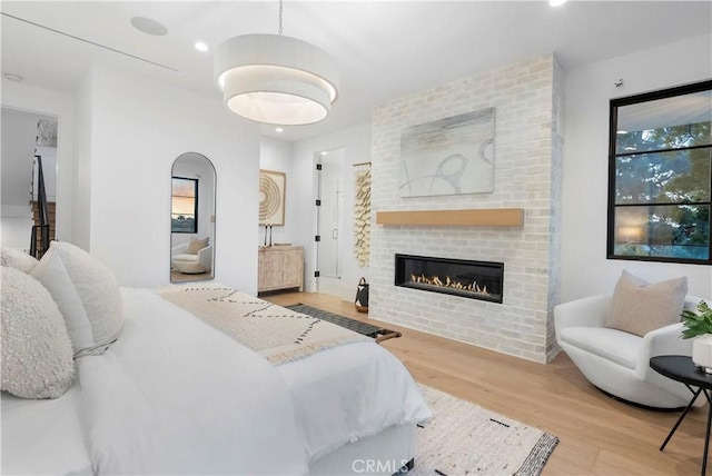 bedroom featuring a brick fireplace, recessed lighting, and wood finished floors