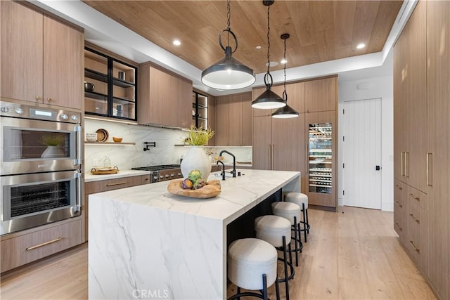 kitchen with wood ceiling, a tray ceiling, light wood-style flooring, stainless steel appliances, and modern cabinets