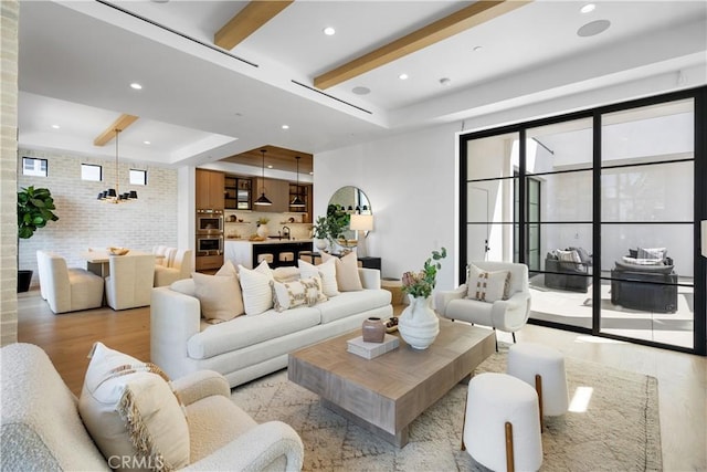 living room featuring brick wall, light wood finished floors, a tray ceiling, recessed lighting, and beamed ceiling