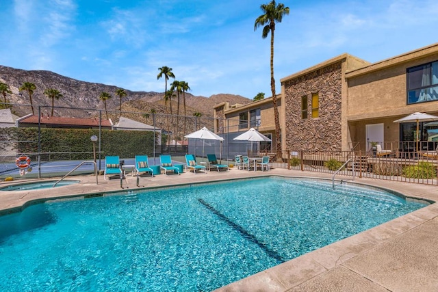 view of pool featuring a mountain view, a community hot tub, and a patio