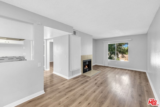 unfurnished living room with light hardwood / wood-style floors and a textured ceiling