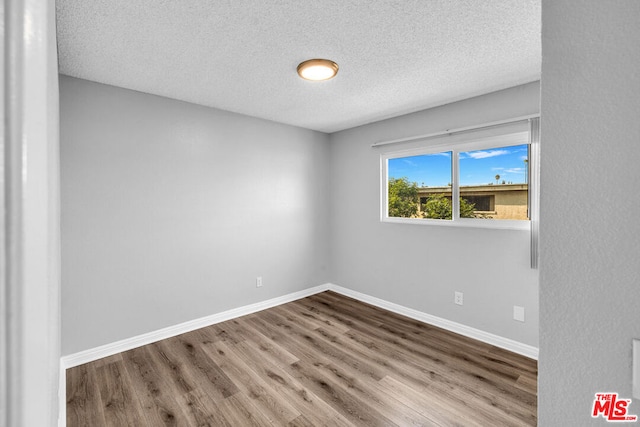 unfurnished room with wood-type flooring and a textured ceiling