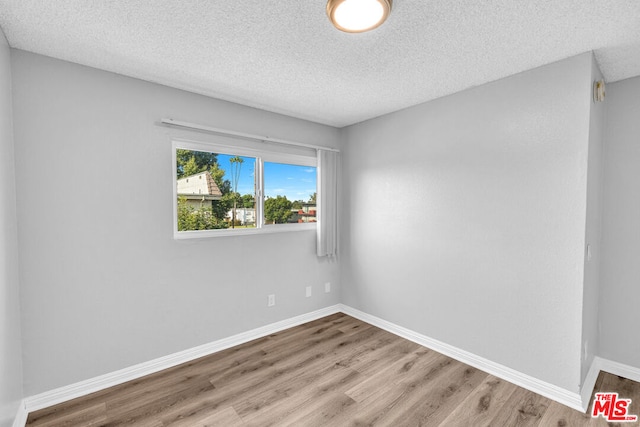 unfurnished room with light hardwood / wood-style flooring and a textured ceiling