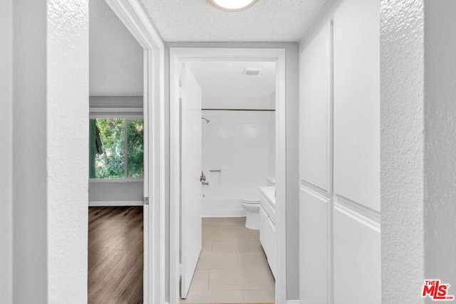 corridor featuring light hardwood / wood-style floors and a textured ceiling