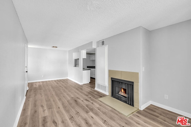 unfurnished living room with a textured ceiling, a fireplace, and light hardwood / wood-style floors