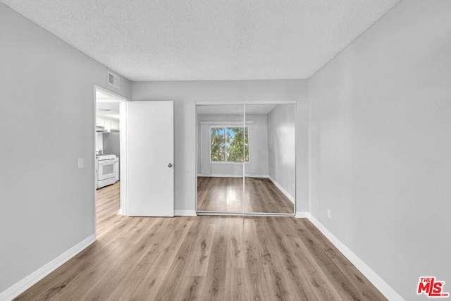 spare room featuring a textured ceiling and light hardwood / wood-style floors