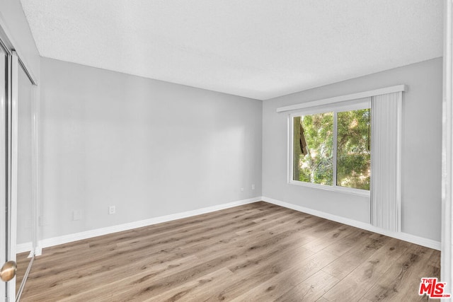 empty room with a textured ceiling and light wood-type flooring