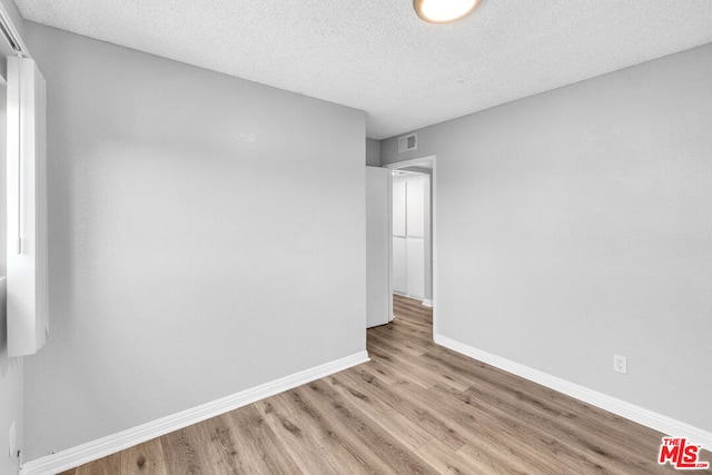 unfurnished room featuring a textured ceiling and light hardwood / wood-style floors