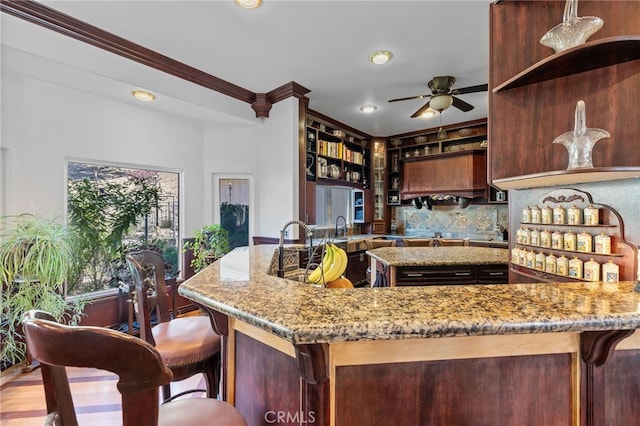 kitchen featuring light hardwood / wood-style floors, light stone counters, ceiling fan, ornamental molding, and sink