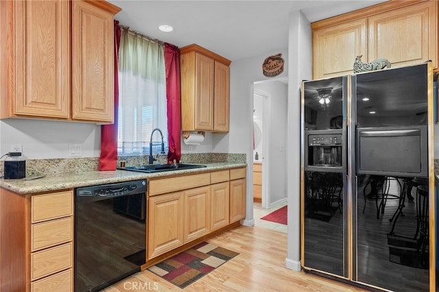 kitchen featuring light stone counters, light wood-type flooring, sink, and black appliances