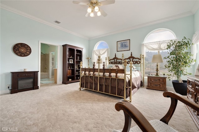 carpeted bedroom featuring ceiling fan, ensuite bath, and crown molding