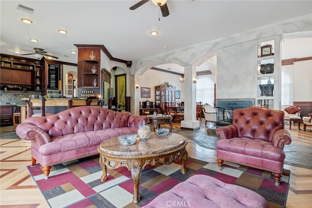 living room featuring ceiling fan, crown molding, and decorative columns